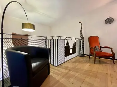 a living room with a black chair and a chair at Côté Cité appartements - Parking privé - 100m Cité médiévale in Carcassonne