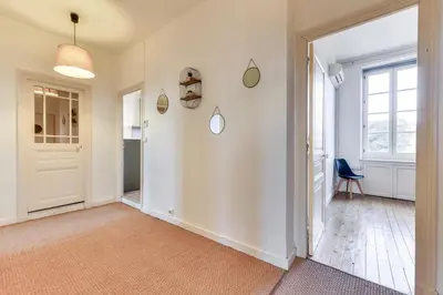 a hallway with white walls and a door and a chair at Le Marty - wifi - central - climatison - parking gratuit in Carcassonne