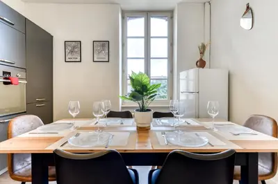a dining room table with chairs and a refrigerator at Le Marty - wifi - central - climatison - parking gratuit in Carcassonne