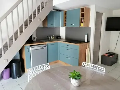 a kitchen with blue cabinets and a table with chairs at Le Bleu du Sud in Gruissan