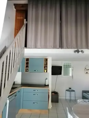 a living room with a staircase and a blue cabinet at Le Bleu du Sud in Gruissan