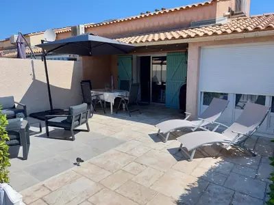 a patio with a table and chairs and an umbrella at Le Bleu du Sud in Gruissan