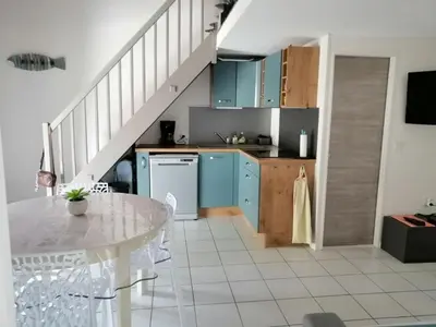 a kitchen with blue cabinets and a white table at Le Bleu du Sud in Gruissan