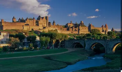 a castle on a hill with a bridge and a river at La Maison du Roi Arthur in Carcassonne