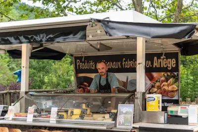 a man is standing behind a food stand at Camping maeva Respire La Serre in Aigues-Vives