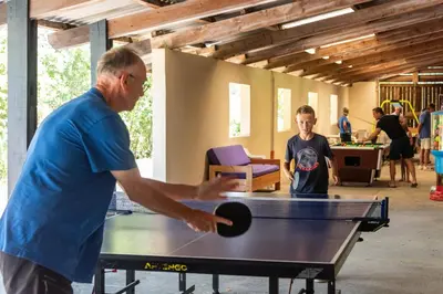 a man and a boy playing table tennis at Camping maeva Respire La Serre in Aigues-Vives