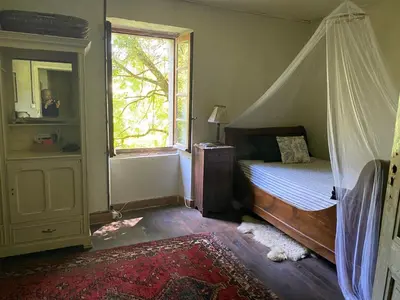 a bedroom with a canopy bed and a window at La Maison dans la forêt in Vabre