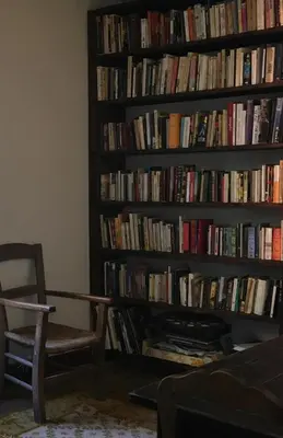 a book shelf filled with books next to a chair at La Maison dans la forêt in Vabre