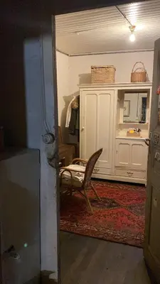 a living room with a chair and a cabinet at La Maison dans la forêt in Vabre