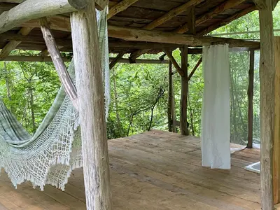 a hammock on the deck of a cabin at La Maison dans la forêt in Vabre