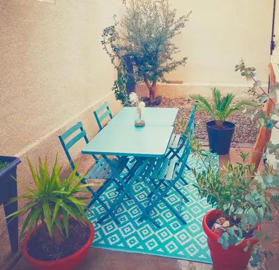a blue table and chairs in a patio with plants at Studio Oasis Narbonne Terrasse & Calme in Narbonne