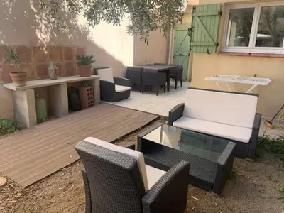 a patio with chairs and tables and a table at L'olivier de Nonna in Gruissan