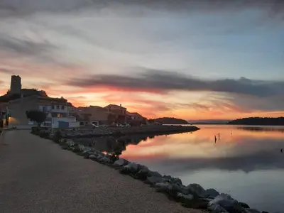 a sunset over a body of water with buildings at L'olivier de Nonna in Gruissan