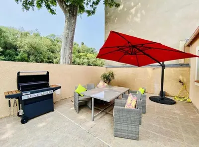 a patio with a table and a grill and a red umbrella at Villa Tamaris in Carcassonne