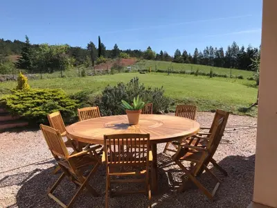 a wooden table with chairs and a potted plant on it at Villa les terre rouges avec piscine dans l ' Aude in Arques