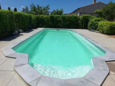 a swimming pool with blue water in a yard at Villa les terre rouges avec piscine dans l ' Aude in Arques