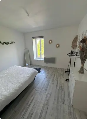 a bedroom with a white bed and a wooden floor at Appartement T3 in Marseillette