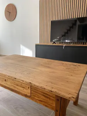 a wooden table in a room with a clock at Le gîte du bonheur in Dalou