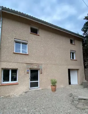 a brick house with a potted plant in front of it at Le gîte du bonheur in Dalou