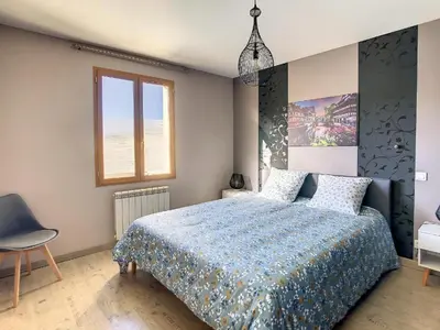 a bedroom with a bed with a blue comforter and a window at La Cigotà - Villa with swimming pool for 8 people in Pouzols-Minervois