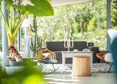a woman sitting in a chair in a living room with plants at Évasion champêtre à Horizon P'y - Piscine in Puéchoursi