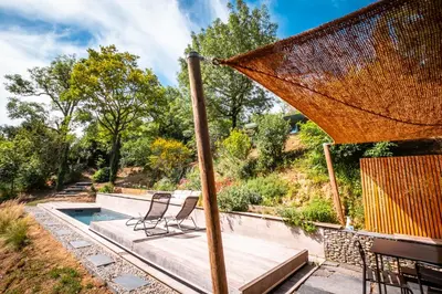 a patio with two chairs and an umbrella at Évasion champêtre à Horizon P'y - Piscine in Puéchoursi