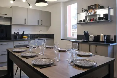 a wooden table with glasses and plates on it in a kitchen at Magnifique*T4*centre ville*WIFI*Billard*Netflix* in Limoux