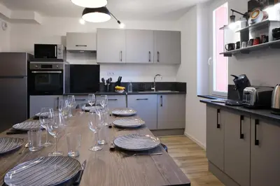 a kitchen with a wooden table with plates and wine glasses at Magnifique*T4*centre ville*WIFI*Billard*Netflix* in Limoux