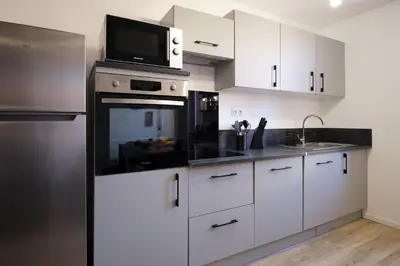 a kitchen with white cabinets and a microwave at Magnifique*T4*centre ville*WIFI*Billard*Netflix* in Limoux