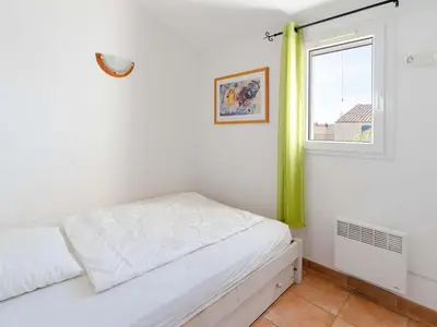a white bedroom with a bed and a window at Pavillon climatisé 4 pièces avec WIFI, proche plage, terrasse, barbecue, park. privatif, animaux admis - FR-1-409-249 in Gruissan