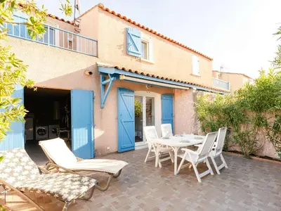 a patio with a table and chairs and a building at Pavillon climatisé 4 pièces avec WIFI, proche plage, terrasse, barbecue, park. privatif, animaux admis - FR-1-409-249 in Gruissan