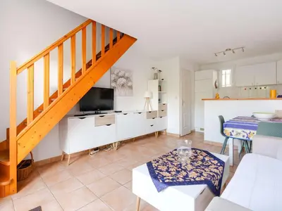 a living room with a staircase and a kitchen at Pavillon climatisé 4 pièces avec WIFI, proche plage, terrasse, barbecue, park. privatif, animaux admis - FR-1-409-249 in Gruissan