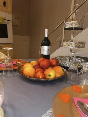a plate of fruit on a table with a bottle of wine at Maison chaleureuse à Capendu avec cheminée et jardin in Capendu