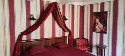 a bedroom with a bed and a red and white striped wall at Suite Napoléon - La Halte d'Eugénie in Félines-Termenès