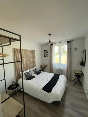 a bedroom with a bed with white sheets and black pillows at T4 Lumineux proche Centre Ville Narbonne & Des Grands Buffets 2 étoiles in Narbonne