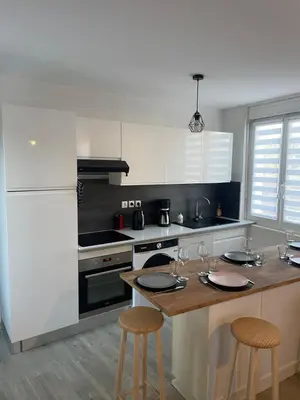 a kitchen with a table with two stools and a stove at T4 Lumineux proche Centre Ville Narbonne & Des Grands Buffets 2 étoiles in Narbonne