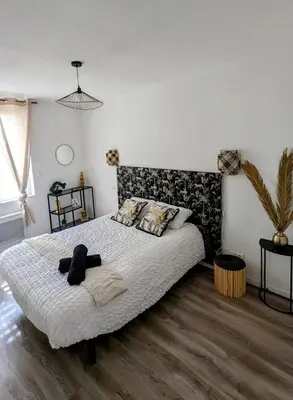 a bedroom with a bed with a black and white comforter at T4 Lumineux proche Centre Ville Narbonne & Des Grands Buffets 2 étoiles in Narbonne