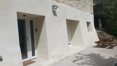a white building with a door and a picnic table at Un Petit Coin Douillet au Pradel in Montredon-Labessonnié