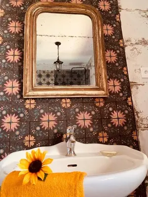 a bathroom sink with a mirror and a flower on it at La Babayaga in Capestang