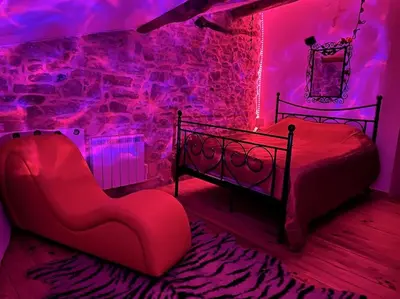 a bedroom with a bed and a chair and purple lights at Love room de Blanche Neige in Assignan
