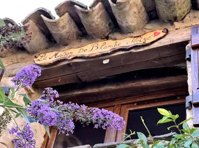 a sign on the side of a building with purple flowers at Love room de Blanche Neige in Assignan