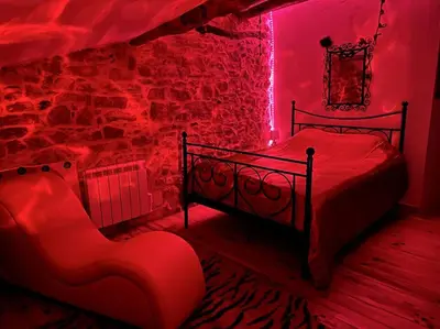 a red room with a bed and a chair at Love room de Blanche Neige in Assignan