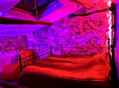 a bedroom with a bed with red and purple lights at Love room de Blanche Neige in Assignan