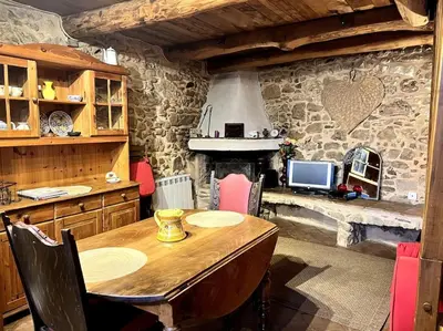 a kitchen with a wooden table and a stone wall at La Maison De Blanche Neige in Assignan