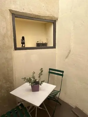 a table and chair with a potted plant on a window at Studio Sanae in Lézignan-Corbières