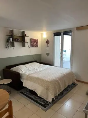 a bedroom with a bed and a large window at Studio Sanae in Lézignan-Corbières