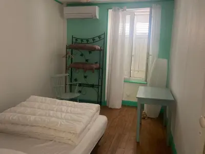 a small room with a bed and a table and a window at Maison RASSIER, Gîte Vélo in Sainte-Eulalie
