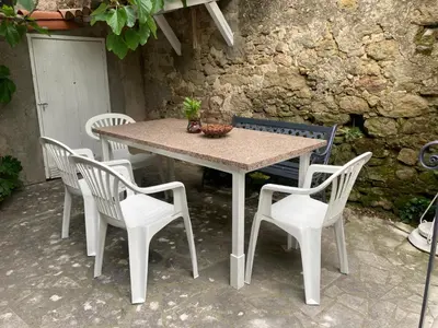 a table and four chairs and a table and a wall at Maison RASSIER, Gîte Vélo in Sainte-Eulalie