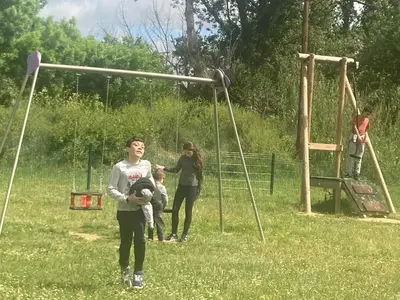 a woman and two children on a playground at Maison RASSIER, Gîte Vélo in Sainte-Eulalie