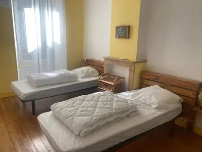 two twin beds in a room with a fireplace at Maison RASSIER, Gîte Vélo in Sainte-Eulalie